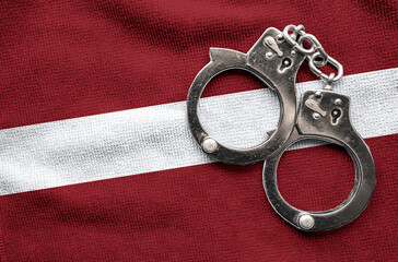 Flag of Latvia and police handcuffs. Crime and offenses in country Concept
