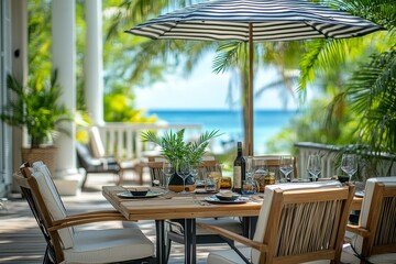 Fototapeta premium Black and white striped umbrella over outdoor dining table with clean-lined chairs, tropical balcony, and palm trees.