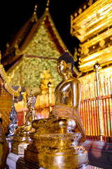 Golden Buddha statue in front of a temple at night, Doi Suthep, Chiang Mai, Thailand.