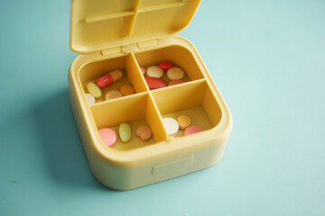 Pill organizer with various medications for daily use on blue surface