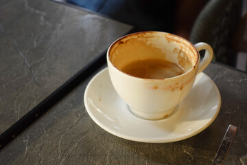 Coffee cup left empty on a table at a cozy cafe in the afternoon