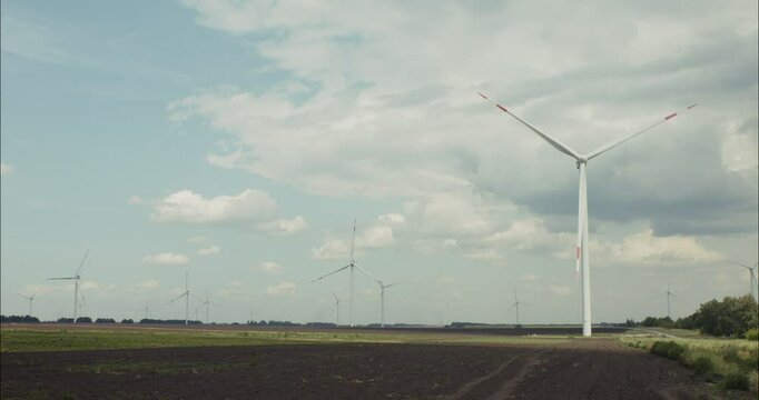 Wind turbines rotating in cultivated field under cloudy sky