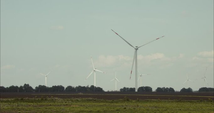 Wind turbines rotating in agricultural landscape under blue sky