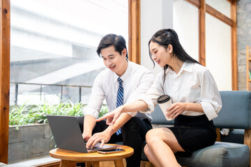 Two people collaborate on a laptop share ideas and review work in a modern office setting