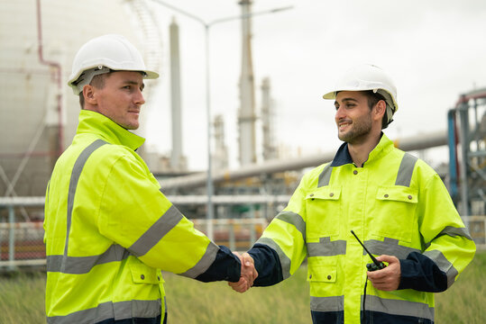Engineer worker hand shaking to colleagues team for success work at construction site of petroleumchemical industry or refinery oil plant factory