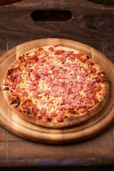 Pizza with ham and mozzarella cheese on wooden background. Soft focus. Close up	