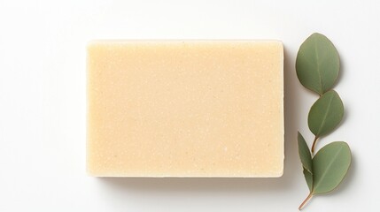 A plain bar of soap rests beside green leaves, highlighting a focus on natural and eco-friendly products for personal care.