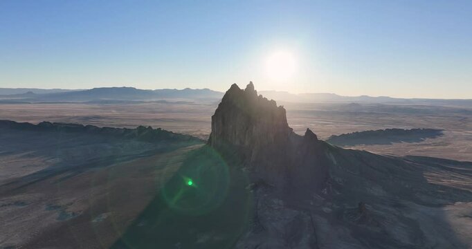 An unworldly, high-contrasted aerial shot of the sacred &ldquo;Ship Rock&rdquo;, a massive, monolithic rock butte, towering above the high desert plain of the Navajo Nation, in New Mexico, as the sun sets behind.