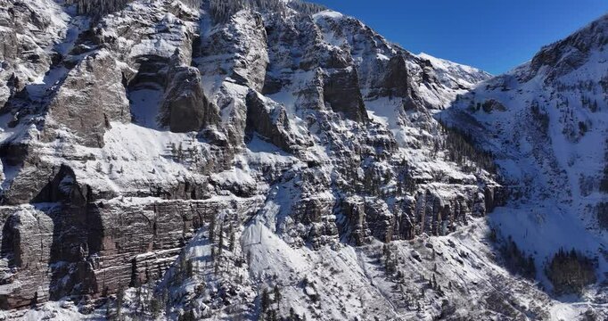 An unworldly aerial drone shot of the extreme Kroger Via Ferrata cliff face and the Black Bear pass switchbacks, slowly rotating backward over the Telluride Valley floor in Western Colorado.