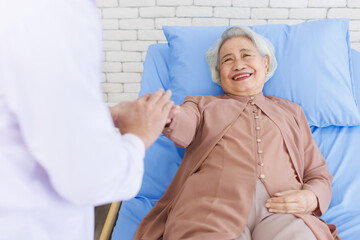 Obraz premium Asian senior woman lay on bed with doctor closeup holding hands with empathy care to trust support or help at hospital, Healthcare elderly patient and medical professional consultation wellness being.