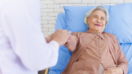Asian senior woman lay on bed with doctor closeup holding hands with empathy care to trust support...