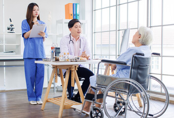 Asian male doctor and caring nurse holding a clipboard talking to old woman patient about ways of treating diagnosis. Healthcare elderly senior consultation medical professional wellness being concept