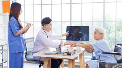 Obraz premium Asian male doctor and caring nurse holding a clipboard talking to old woman patient about ways of treating diagnosis. Healthcare elderly senior consultation medical professional wellness being concept
