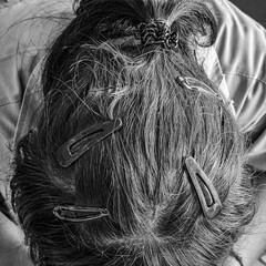 Close-up of a woman’s black hair with hairpin on gray shirt, minimal fashion style, clean look, beauty concept, monochrome tone, natural light.