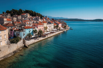 Obraz premium coastal town with white buildings, beach, and turquoise sea. Summer vacation destination.