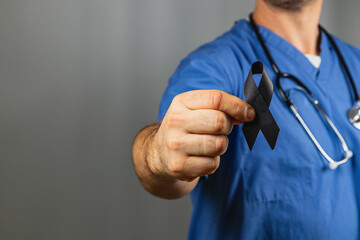 Healthcare worker holding a black ribbon for mourning and support
