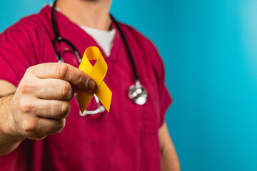 Healthcare professional holds yellow awareness ribbon to show support