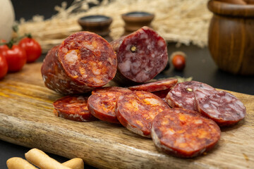 A cured sausage on a wooden board, paired with fresh ingredients to enhance its flavor