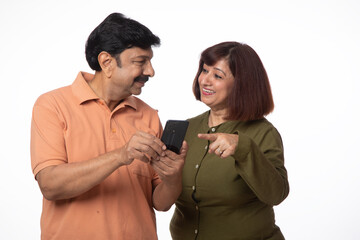 Indian happy senior couple using digital mobile technology on white background. Mobile banking anywhere 