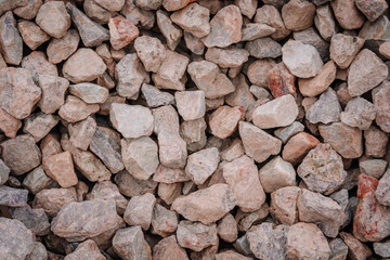 A close-up image of large, angular gray and tan construction rocks forming a textured, natural surface commonly used in heavy-duty groundwork..