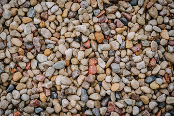 Colorful smooth pebbles of various sizes and shades forming a natural, textured stone background, ideal for decorative or landscaping use..