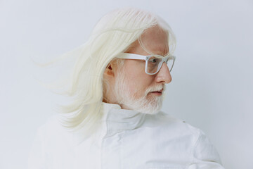 Elderly man with long white hair and glasses wearing a white outfit, looking thoughtfully to the...