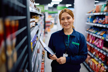 Happy woman working at supermarket and looking at camera.