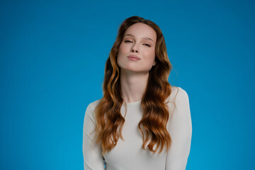 Dynamic woman posing with confidence and emotion in a studio setting against a vibrant blue backdrop