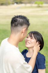Fototapeta premium In the spring scene in May, we see an unmanned park in Jokojicho, Gokojicho, Eri Prefecture. Japanese couples in their early 20s spend time together.They stare at each other by a large tree.