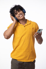 Fototapeta premium Young indian male enjoying music on white. Portrait of a cheerful attractive man in headphones enjoys listening to music while standing and singing isolated over white background