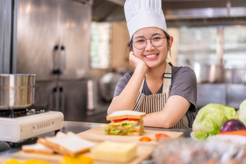 Smiling Young Female Chef in Kitchen with Fresh Sandwich