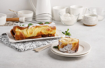 A piece of Finnish pancake in roll with cream on white plate, morning breakfast