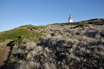 White red lighthouse on the top of grassy hill. Europe old lighthouse, Portugal coastline