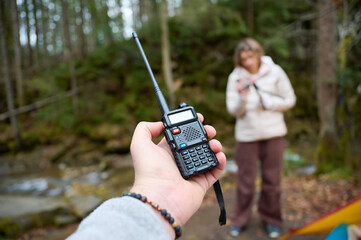 Man holding radio station giving to her girlfriend. Walkie talkie in the mountains. Concept of wireless communications. Off grid communication methods.