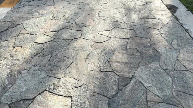 Top-down concrete stone path with sunlight casting natural shadows and patterns
