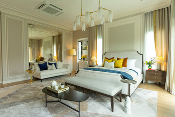 Spacious master bedroom with large area rug, wood floor, white ceiling lamp and several windows.