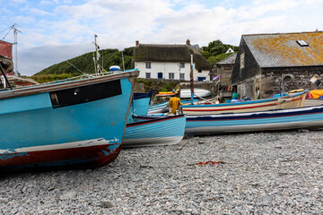 Fishing boats on the beach and traditional thatch cottage in the fishing port of Cadgwith Cove on Cornwall’s Lizard Peninsula