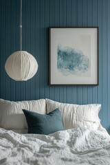 A bedroom with a white bed, white pillows, a blue pillow, and a framed abstract painting hanging on a teal wall