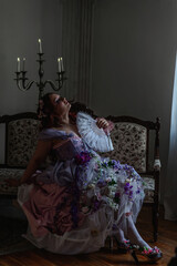 A girl dressed in the style of a Victorian boudoir, in a corset and crinoline of lilac color, in flowers