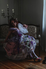 A girl dressed in the style of a Victorian boudoir, in a corset and crinoline of lilac color, in flowers
