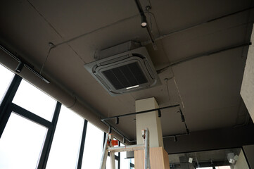 Ceiling mounted cassette air conditioner in modern building. Loft style. Industrial interior design.