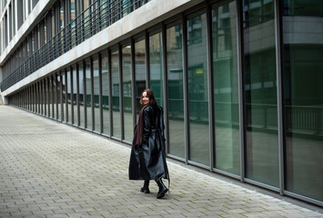 Woman walking away in front of an office building on the streets of Stuttgart, Germany