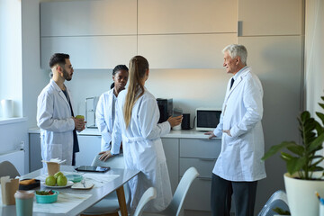 Group of scientists engaged in active discussion in bright, modern laboratory discussing research findings. Room filled with scientific equipment and casual workspace atmosphere
