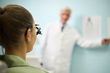 Obraz premium Patient attended examination with an ophthalmologist who is blurred in background. Professional setting with medical focus in an eye clinic, ensuring patient's visual health