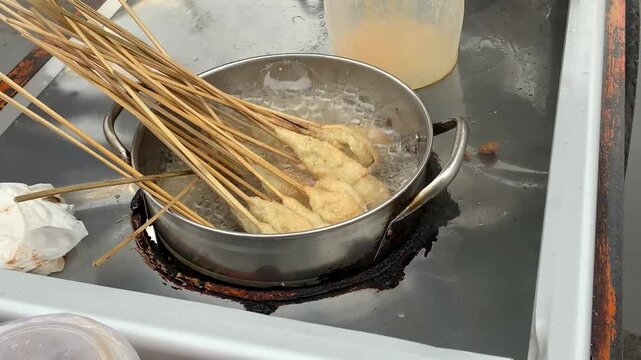 Sempol, Indonesian street food made from tapioca and chicken, simmers in hot oil on a street vendor's cart in Jakarta.
