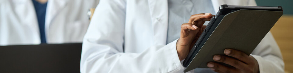 Medical professional using digital tablet in a healthcare environment. Image shows focus on hands...