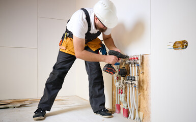 Man adjusting the heating system in a new apartment. Plumber adjusting heat on the central system valves. Service man adjusting house heating system. Underfloor heating system. Man checking pipe