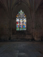 Stained glass window in old church. Vaulted ceiling, dimly lit, tranquil atmosphere, and a glowing,...