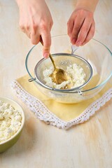 Rubbing cottage cheese through a metal sieve to give it a more delicate texture for making cottage cheese desserts or Easter dishes. Cottage cheese dishes.