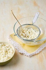 Rubbing cottage cheese through a metal sieve to give it a more delicate texture for making cottage cheese desserts or Easter dishes. Cottage cheese dishes.